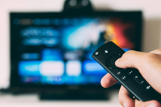 A person holding a TV remote and browsing a selection of TV series on a streaming platform