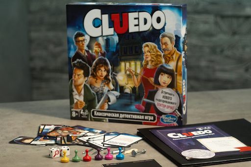A Russian edition of Cluedo, with the game box standing upright and the cards and rulebook laid out on a table.