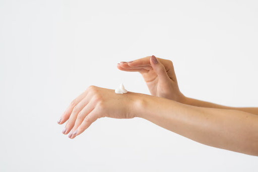 A close-up of hands, with cream on one hand and the other hand hovering above it, ready to apply